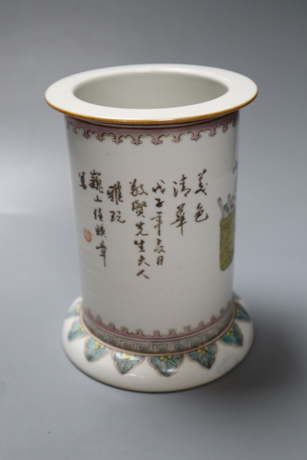 A Chinese cylindrical porcelain brush pot, enamelled with female figures and script, 15cm